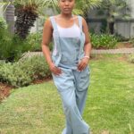 A woman in Johannesburg wearing a stylish denim overalls jumpsuit, paired with a white tank top, offering a comfortable and casual streetwear look.
