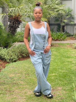 A woman in Johannesburg wearing a stylish denim overalls jumpsuit, paired with a white tank top, offering a comfortable and casual streetwear look.